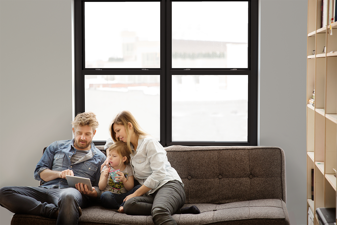 Family viewing tablet computer in living room with impact resistant window