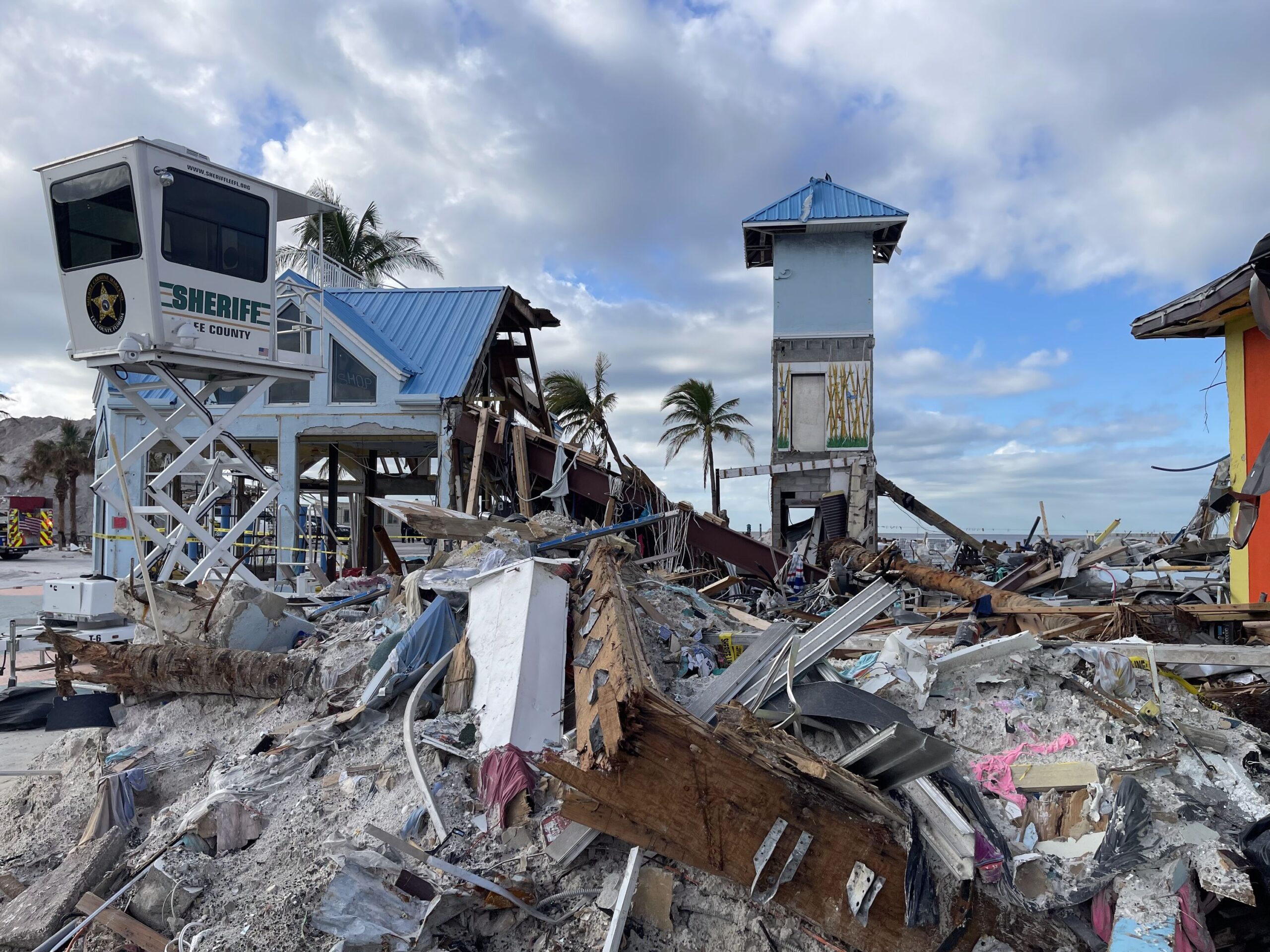 A beach area is covered by destroyed buildings, sand, concrete and other debris.