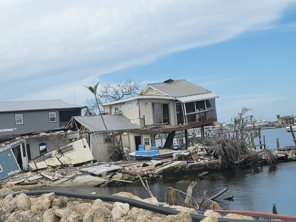 This image shows the aftermath of a hurricane, with a waterfront home demolished by the storm.